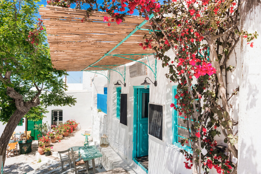 Traditional street with cute cafe bars in Greece beautiful colorful Greek houses with flowers in Amorgos Chora Cyclades Greece