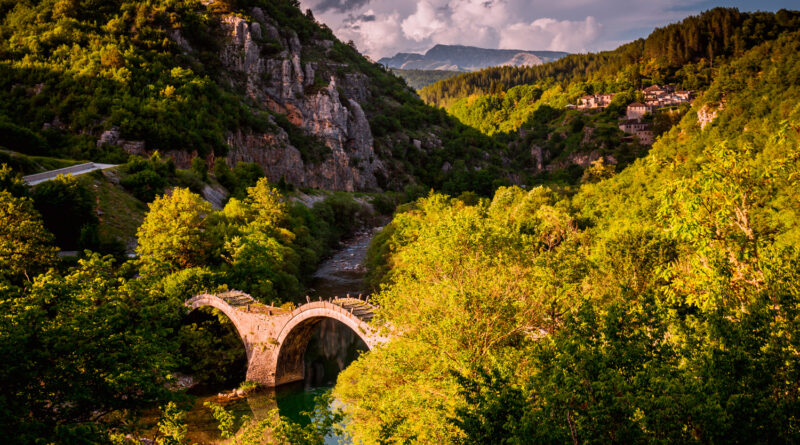 Plakidas Bridge with Kipi village in background - Arches stone bridge of Kalogeriko on river Voidomatis Central Zagoria Epirus Greece