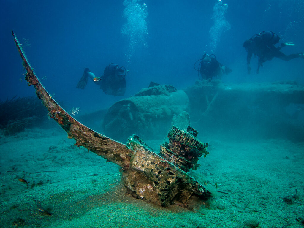 Scuba divers exploring ruined Messerschmitt at the bottom of the sea in Hersonissos, Crete Greece