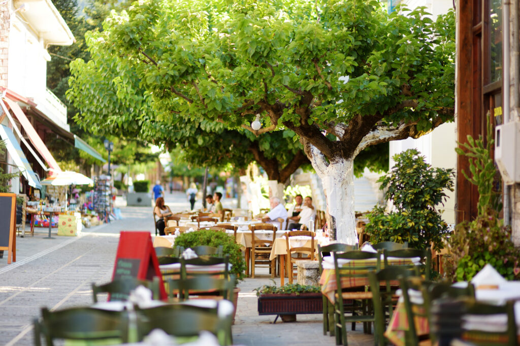 Small outdoor restaurants and cafes at the pedestrian area at center of Kalavryta town near the square and odontotos train station, Greece.